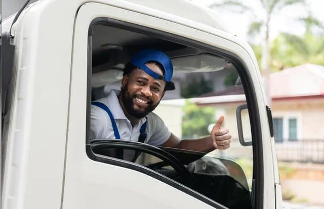 A delivery driver smiling from a truck window (stock photo)