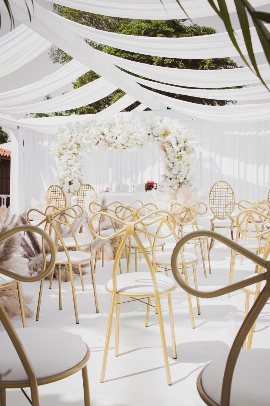 Gold bow-back chairs under white drapes