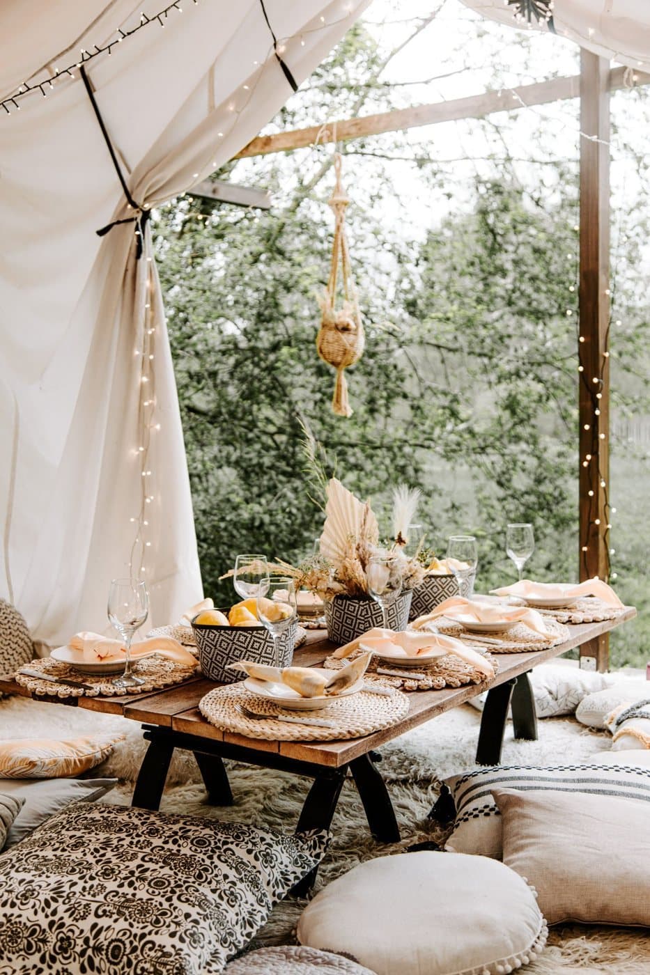 A low boho dining table with cushions under a canopy (stock photo)