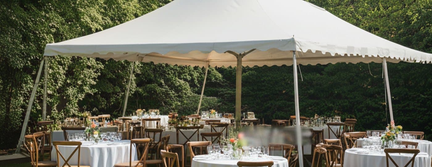 A garden marquee with round tables and wooden chairs (stock photo)
