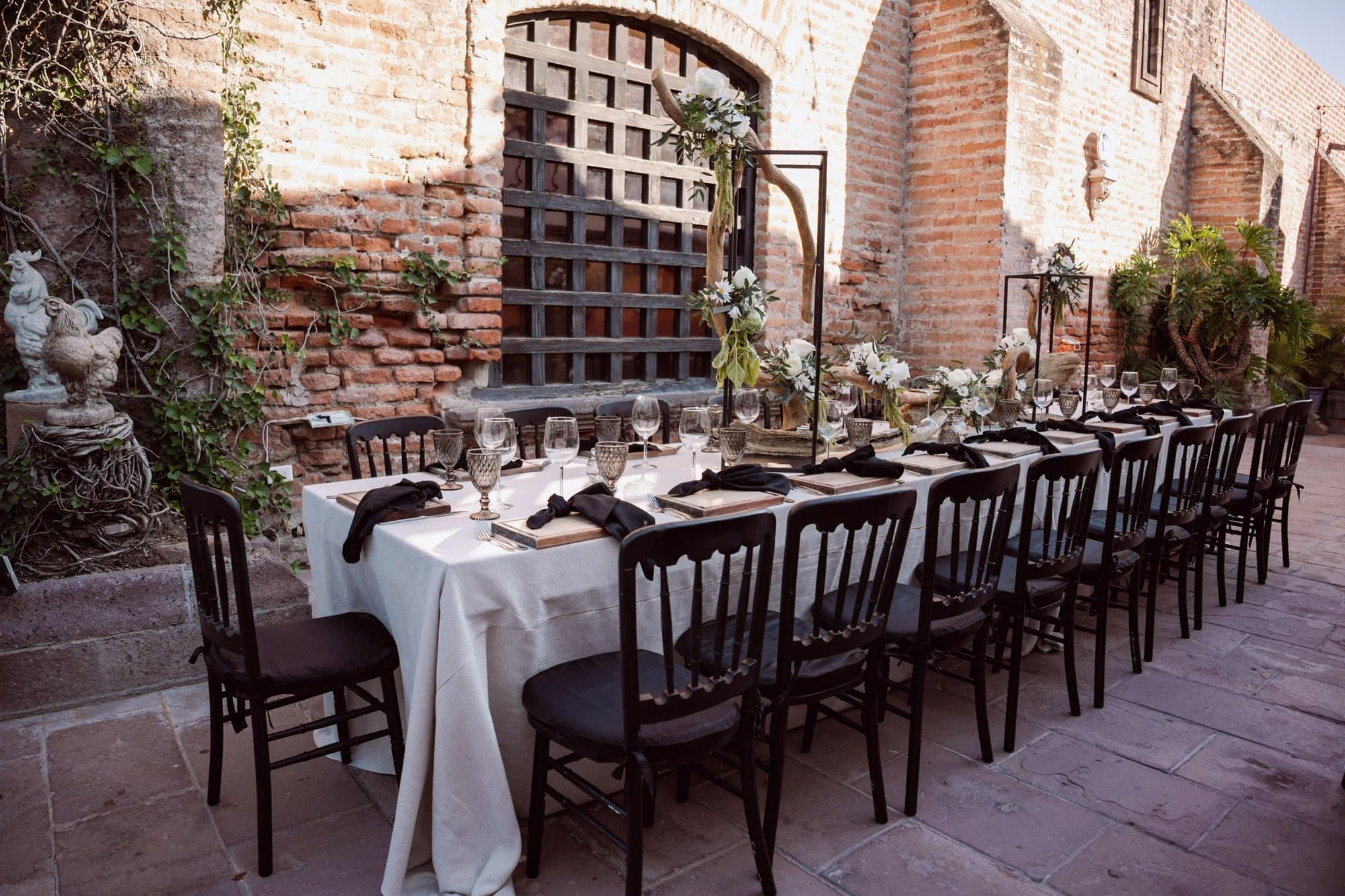 A long table with black chairs in a brick courtyard (stock photo)