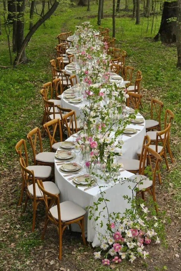 A long oval table with wooden chairs in a spring forest (stock photo)